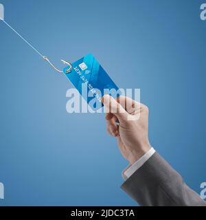 Thief stealing a businessman's credit card with a hook, phishing and frauds concept Stock Photo