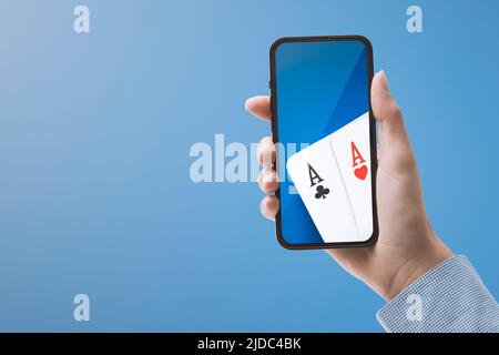 Woman playing poker online on her smartphone, casino and online gambling games concept Stock Photo