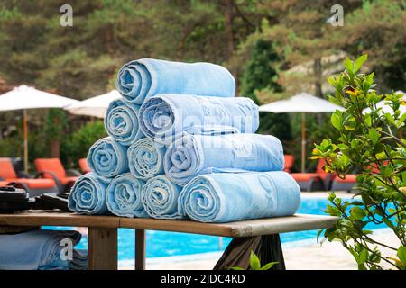 Rolled-up blue terry towels stacked on a pool table. Rolled bath towels in the hotel pool, Spa, relax Stock Photo