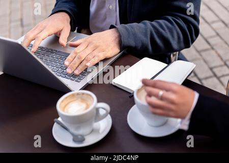 man's hands working with his laptop on a terrace Stock Photo
