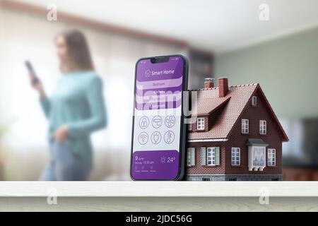Smart home control app on smartphone and model house, home automation concept Stock Photo