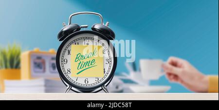Woman having a coffee break in the office, alarm clock in the foreground Stock Photo