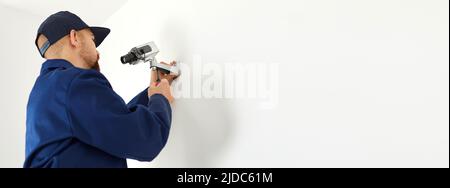 Copy space banner background with man installing CCTV surveillance camera on wall Stock Photo