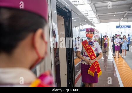 Chongqing. 20th June, 2022. Attendants of train G52 wait for passengers in southwest China's Chongqing Municipality, June 20, 2022. With a total length of 1,068 km, the Zhengzhou-Chongqing High-speed Railway started full operation on Monday. Through the line, travel time from Chongqing to Zhengzhou can be shortened from around 8 hours to 4 hours 23 minutes at the top speed, while the shortest time from Chongqing to Beijing will be cut from more than 20 hours to less than 7 hours. Credit: Tang Yi/Xinhua/Alamy Live News Stock Photo