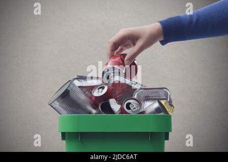 Woman throwing a metal can in the recycling bin, separate waste collection concept Stock Photo