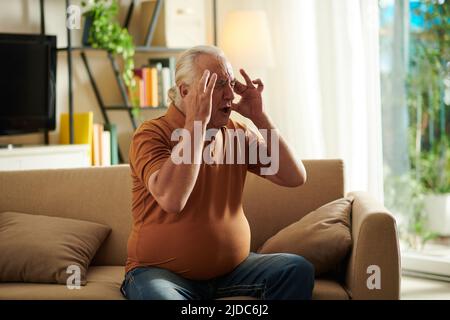 Senior man suffering from severe headache, he is screaming in pain Stock Photo