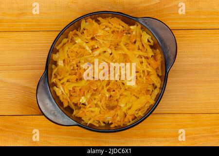 Cabbage stewed in tomato. Homemade steamed cabbage with fresh tomatoes, onions and carrots in a black plate on a wooden table. Healthy, eco-friendly, Stock Photo