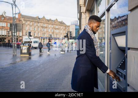 Man withdrawing money from atm in city centre Stock Photo