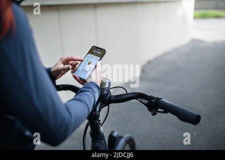 Courier riding a bicycle and looking on the cellphone asnd using delivery app, sustainable transport concept Stock Photo