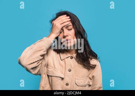 Unhappy millennial caucasian female student in casual holding hand on head and suffering from migraine Stock Photo