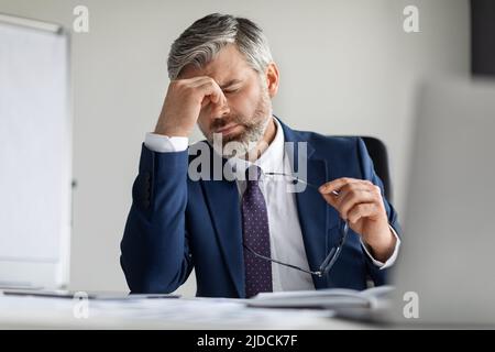 Stressed Middle Aged Businessman Suffering From Headache At Work, Stock Photo