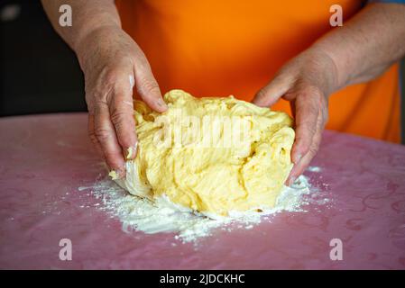 grandmother kneads dough for Easter cakes on the table Stock Photo