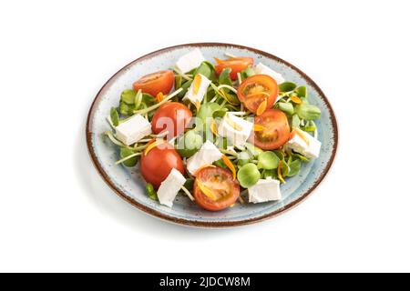 Vegetarian vegetables salad of tomatoes, marigold petals, microgreen sprouts, feta cheese isolated on white background. Side view, close up. Stock Photo