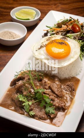 Traditional cambodian Lok Lak stir fried beef with rice meal on wood table background Stock Photo