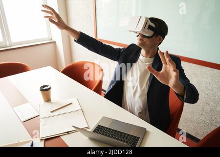 Office clerk looking at virtual reality simulation through headset Stock Photo