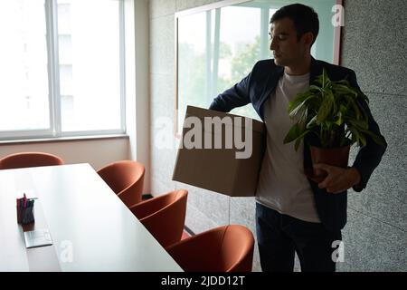 Fired worker carrying box with belongings and plant Stock Photo