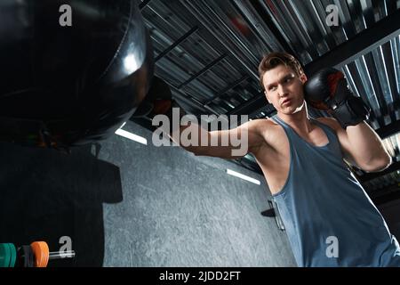 Focused muscular guy training in boxing gloves Stock Photo