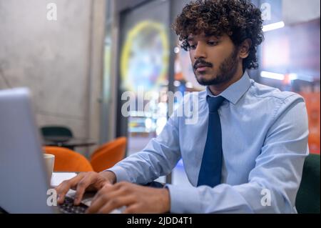 Man typing on laptop while sitting at table Stock Photo
