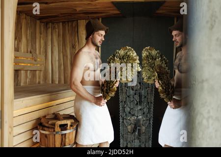 Handsome man with an attractive body enjoys relaxing in the sauna Stock Photo