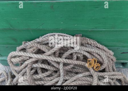 Old rope from a boat over a green wooden background. Patagonia, Argentina. Stock Photo