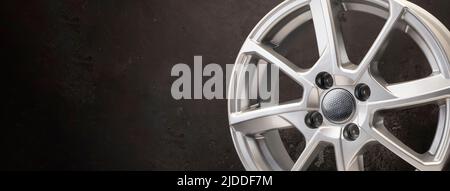 new grey alloy wheels on a dark textured black background. car wheel , copy space panorama empty space. Stock Photo