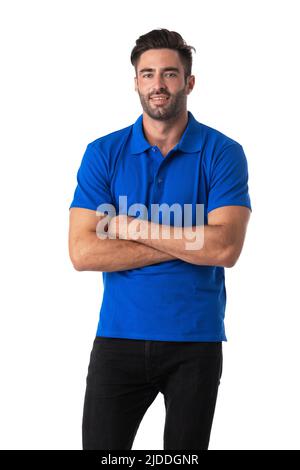 Attractive cheerful young man wearing blue t-shirt standing isolated over white background, arms folded Stock Photo