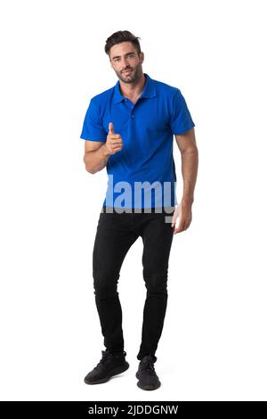 Successful young casual man showing thumbs up looking at camera. Full body length portrait isolated over white background. Stock Photo