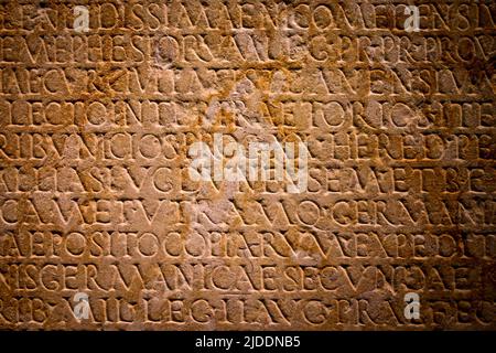 Latin text written in stone. Full frame Roman text carved into a flat stone wall. Stock Photo
