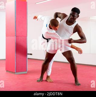Man training throws on trainer during judo training Stock Photo
