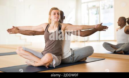 Yoga teacher helps couples learn yoga poses Stock Photo