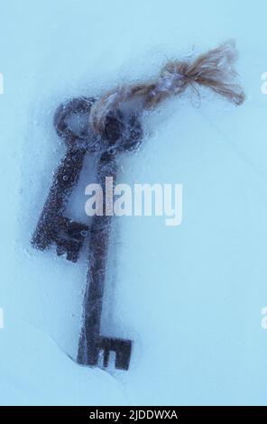 Two rusty deadlock vintage keys tied together with string in sheet of ice Stock Photo