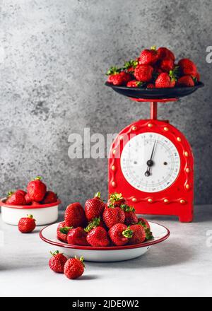 Freshly picked organic strawberries from the garden in white enamel plates and vintage kitchen red scale on background. Stock Photo