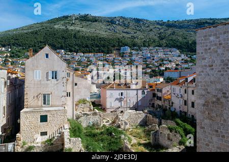 Mount Srđ looms over the heart of Dubrovnik as viewed from the ruins and old buildings of Old Town Stock Photo