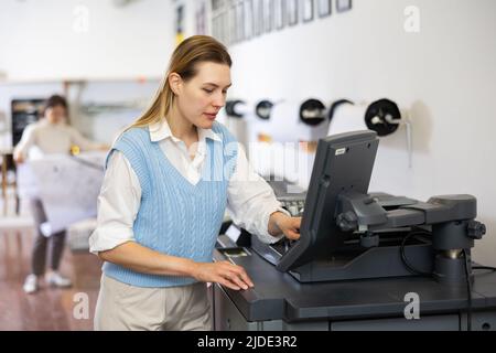 Technician operator calibrating plotter machine, typing on computer keyboard Stock Photo
