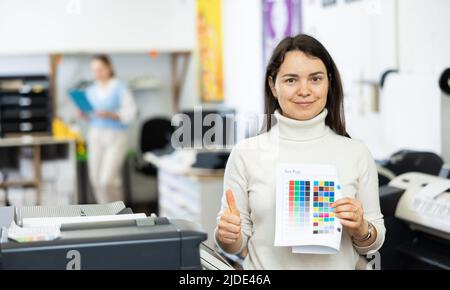 Positive woman publishing facility worker with colour test page Stock Photo