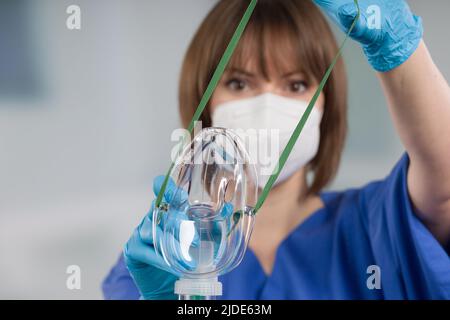 nurse is applying disposable oxygen mask for breathing support from patient view Stock Photo