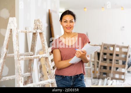 Positive woman designer with documents in construction site Stock Photo