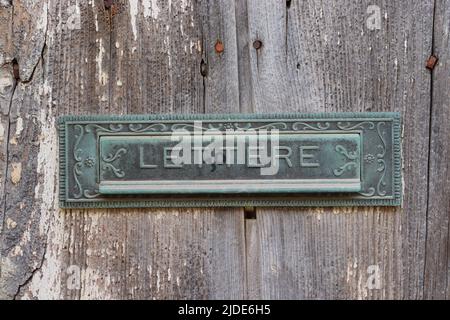 Ornate letter box on an old rustic sun bleached wooden door,  Xaghra, Gozo, Malta. Stock Photo