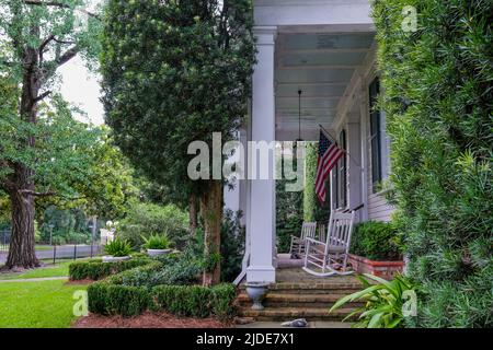 NEW ORLEANS, LA, USA - JUNE 17, 2022: Side view of front porch of vintage home with rocking chairs and American flag Stock Photo