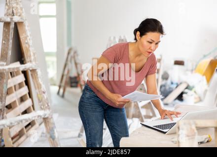 Woman construction manager checking project documentation, using laptop Stock Photo