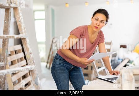 Female architect using laptop during repair works Stock Photo