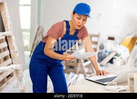Woman worker checking documents and using laptop in construction site Stock Photo