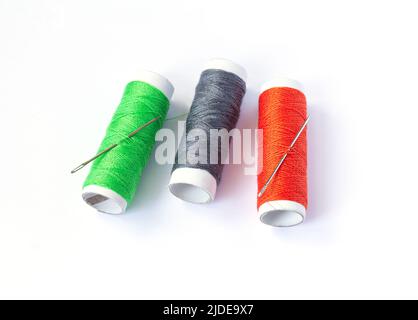 Three spools of sewing threads with needle, set of seamstress isolated on white background. Stock Photo