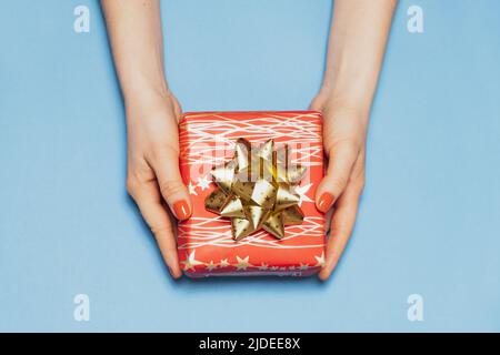 Beautiful red gift box with bow in women's hands, top view, copy space for text Stock Photo