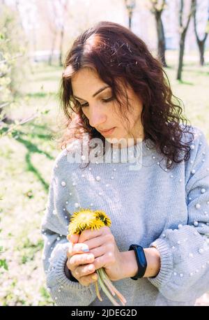 Portrait of a young brunette woman in spring in a park with dandelions Stock Photo