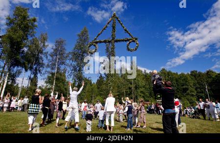 Raising and dancing around a maypole during a midsummer celebration in Sweden. Stock Photo