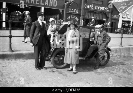 1930, historical, a famliy standing by their motorcar for a photo on a cobbled stone slipway at the seafront at Cleethorpes, Lincolnshire, England, UK. All family members are formally dressed and wearing hats, which for a trip to the seaside was the norm in this era. Stock Photo