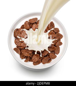 Chocolate corn flakes with pouring milk isolated on white background, top view Stock Photo
