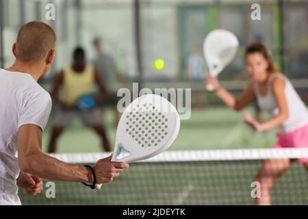 Man playing a padel game in a blue court with his racket Stock Photo ...