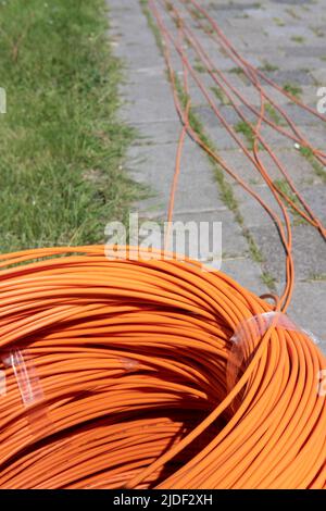 Bundle of coiled orange fiber optic cables on the street, ready to go into the ground. Fast internet. Focus in front Stock Photo